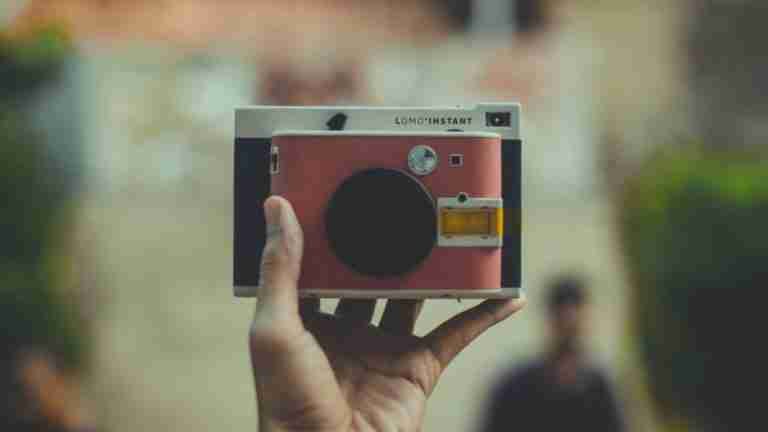 A person framing their face with a colorful instant camera, focus on creativity and quick payday loans photography.