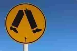 Pictogram of two legs walking on a yellow circular sign against a blue sky, indicating where can I get loans for a pedestrian crossing or walking area.