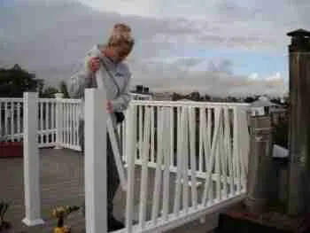 A person standing on a rooftop deck with a white railing, holding onto the gate under a cloudy sky. home improvement loans