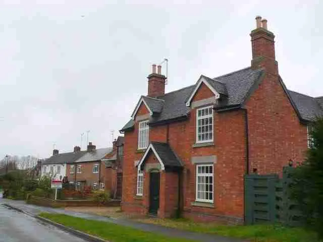 A quiet, overcast day on a residential street with traditional brick houses featuring prominent chimneys and gabled roofs. quick secured loans