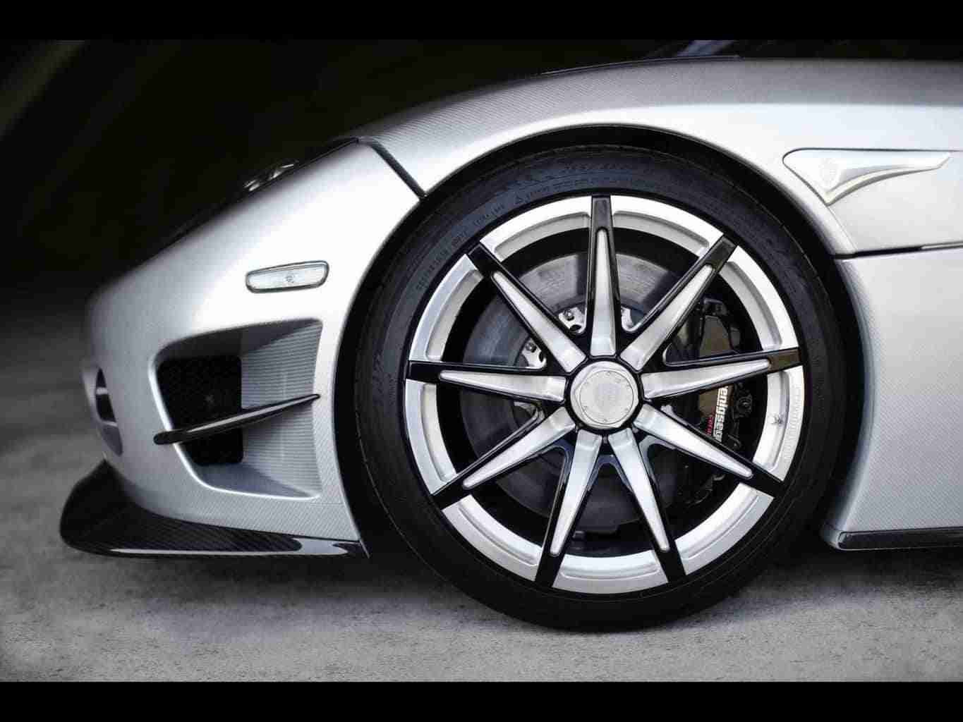 Close-up of a silver sports car's front wheel and aerodynamic vent detail. car finance