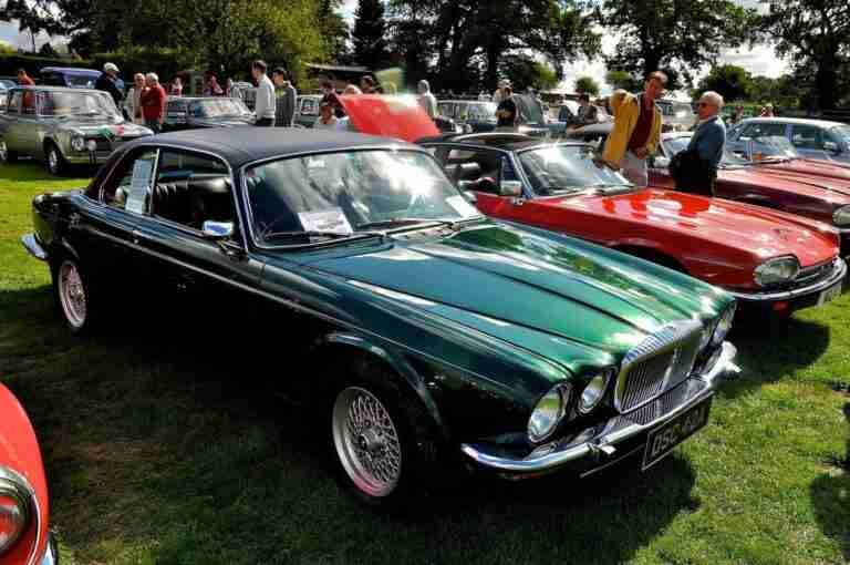 A classic car show featuring vintage vehicles, including a gleaming green jaguar, with spectators admiring the collection on a sunny day. used car financing bad credit
