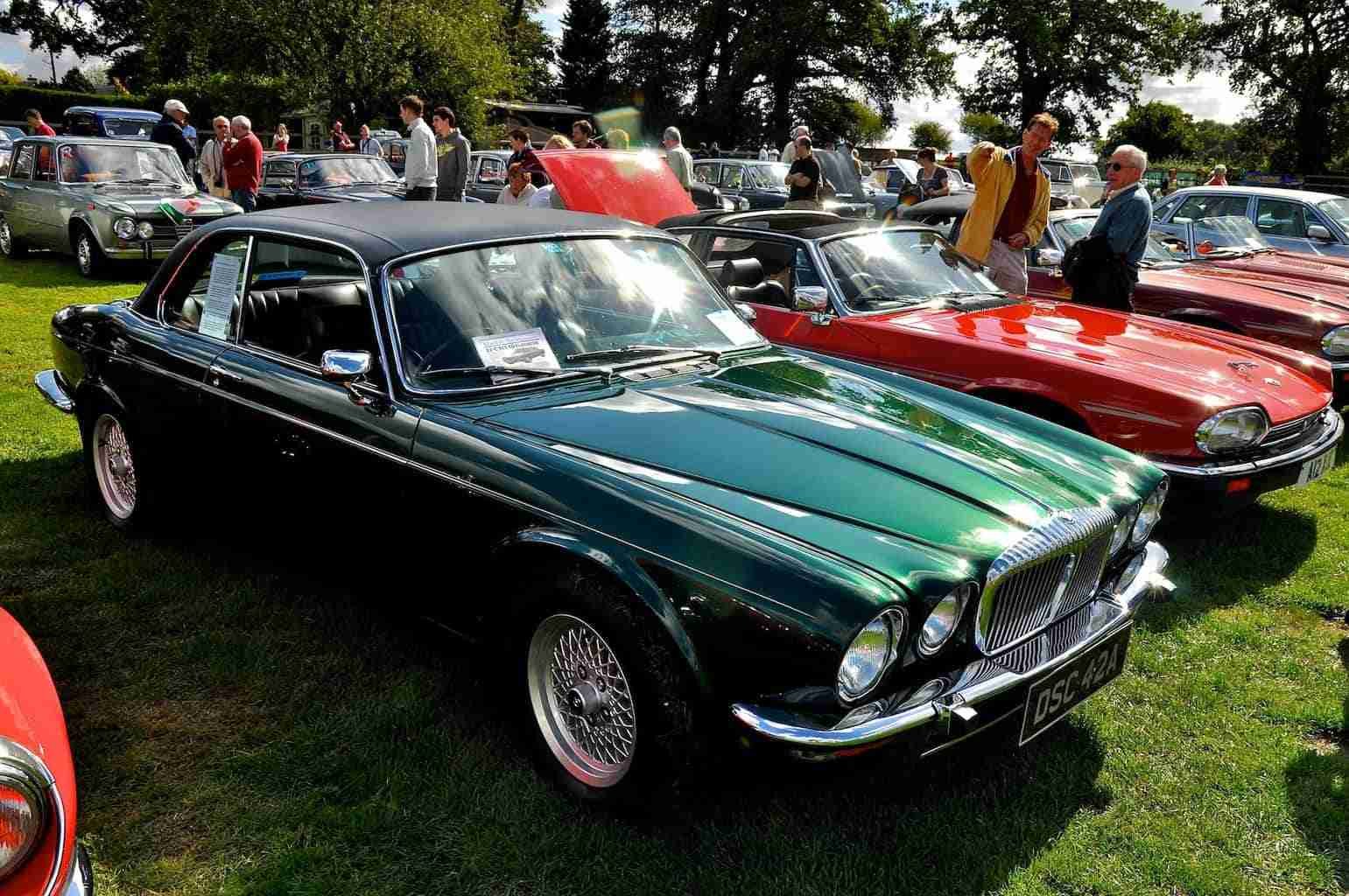 A classic car show featuring vintage vehicles, including a gleaming green jaguar, with spectators admiring the collection on a sunny day. used car financing bad credit