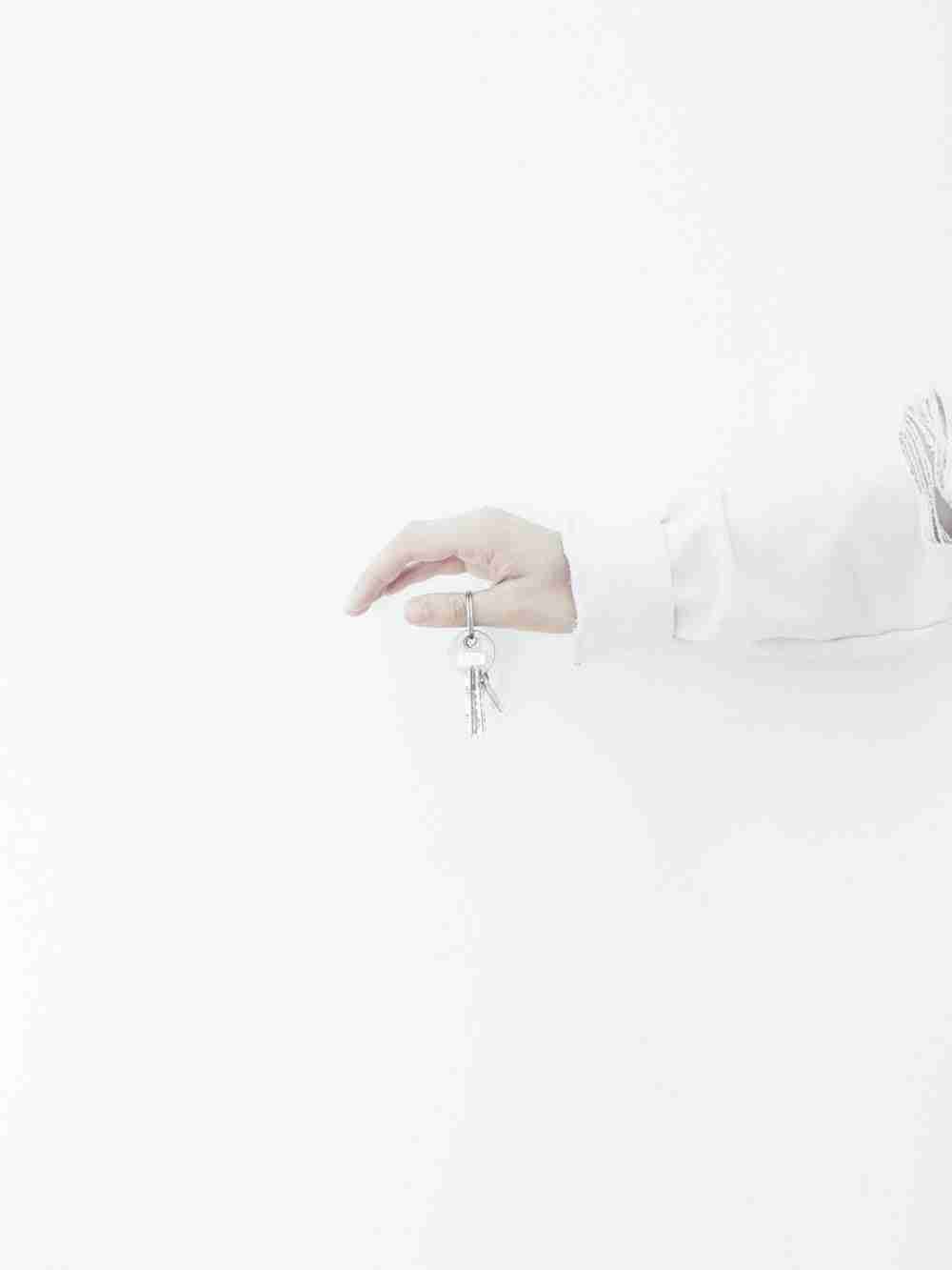 Hand holding keys against a white background. new homeowner loans bad credit