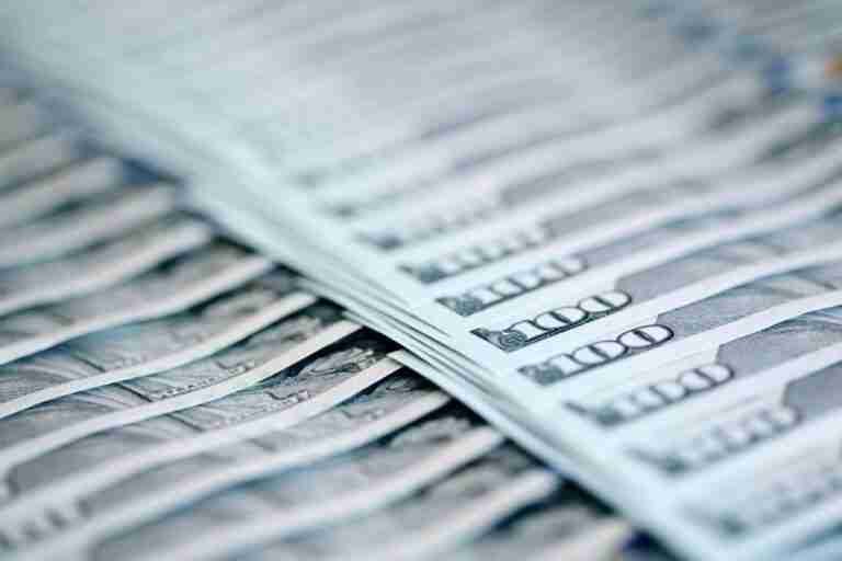 A close-up of a stack of us 100-dollar bills fanned out with a focus on the currency denomination.