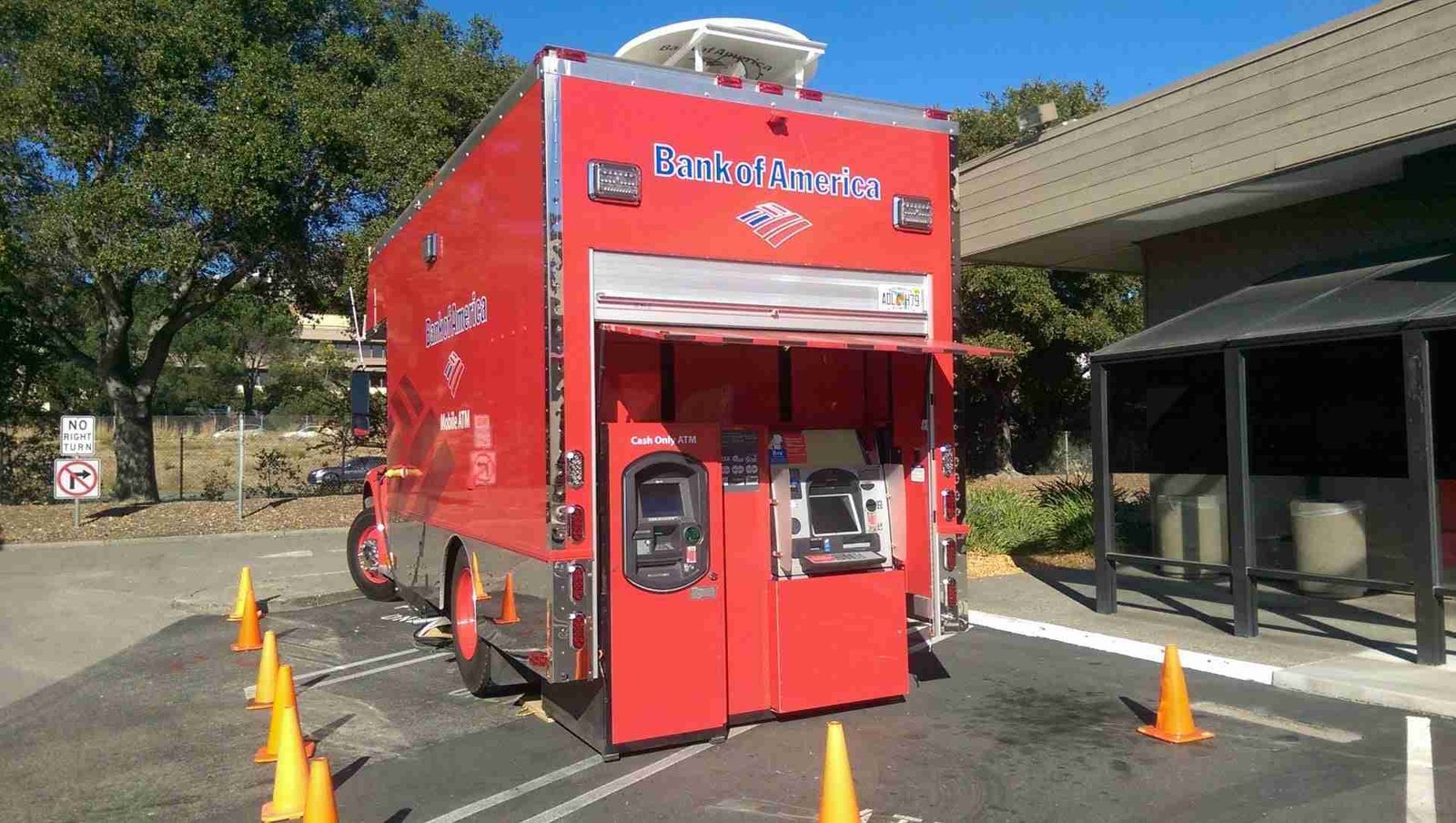 A mobile bank of america atm unit set up in a parking lot, surrounded by orange traffic cones for safety and accessibility. auto bank finance