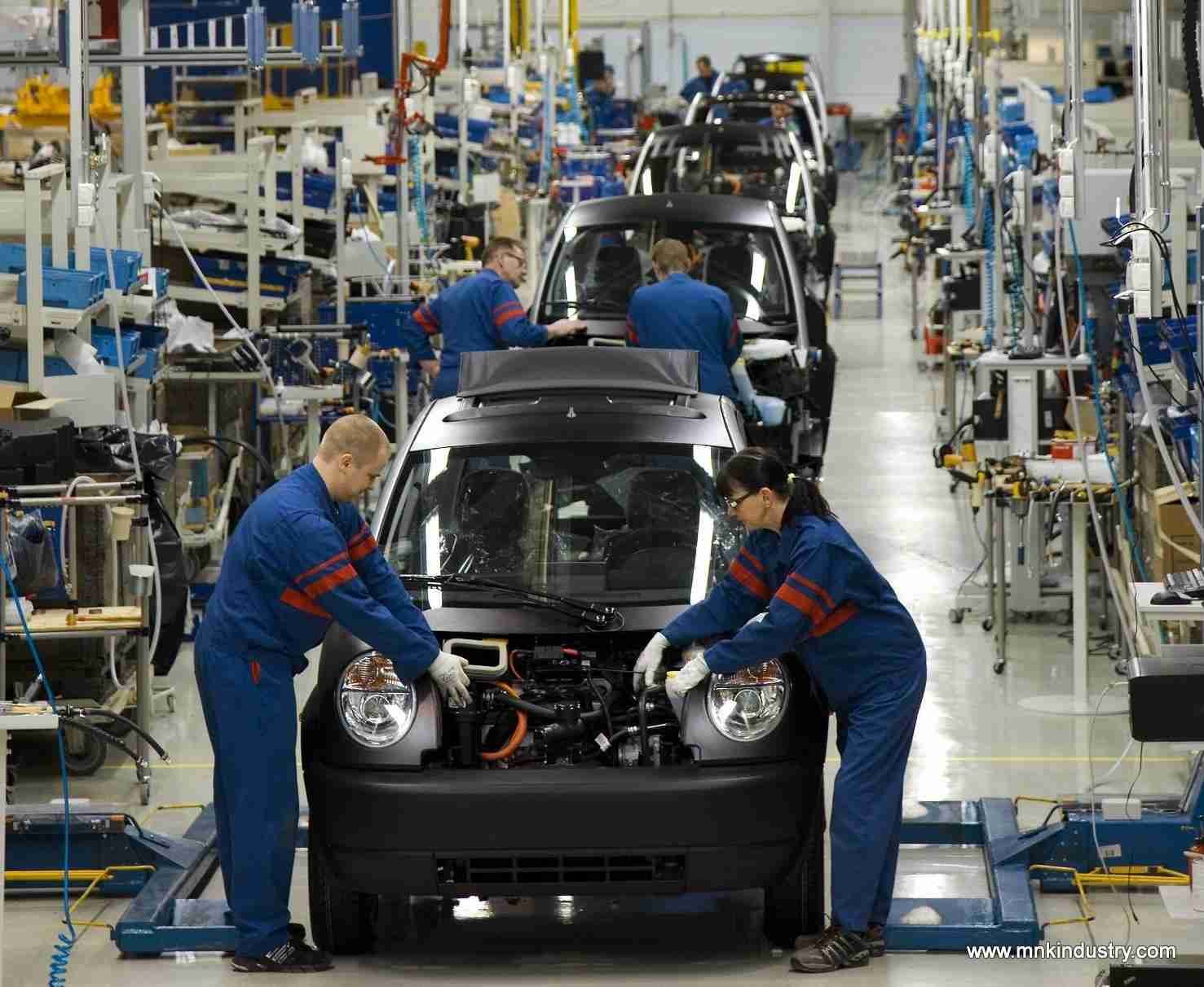 Workers in blue uniforms assembling cars on a production line in an automotive factory. auto loans bad credit