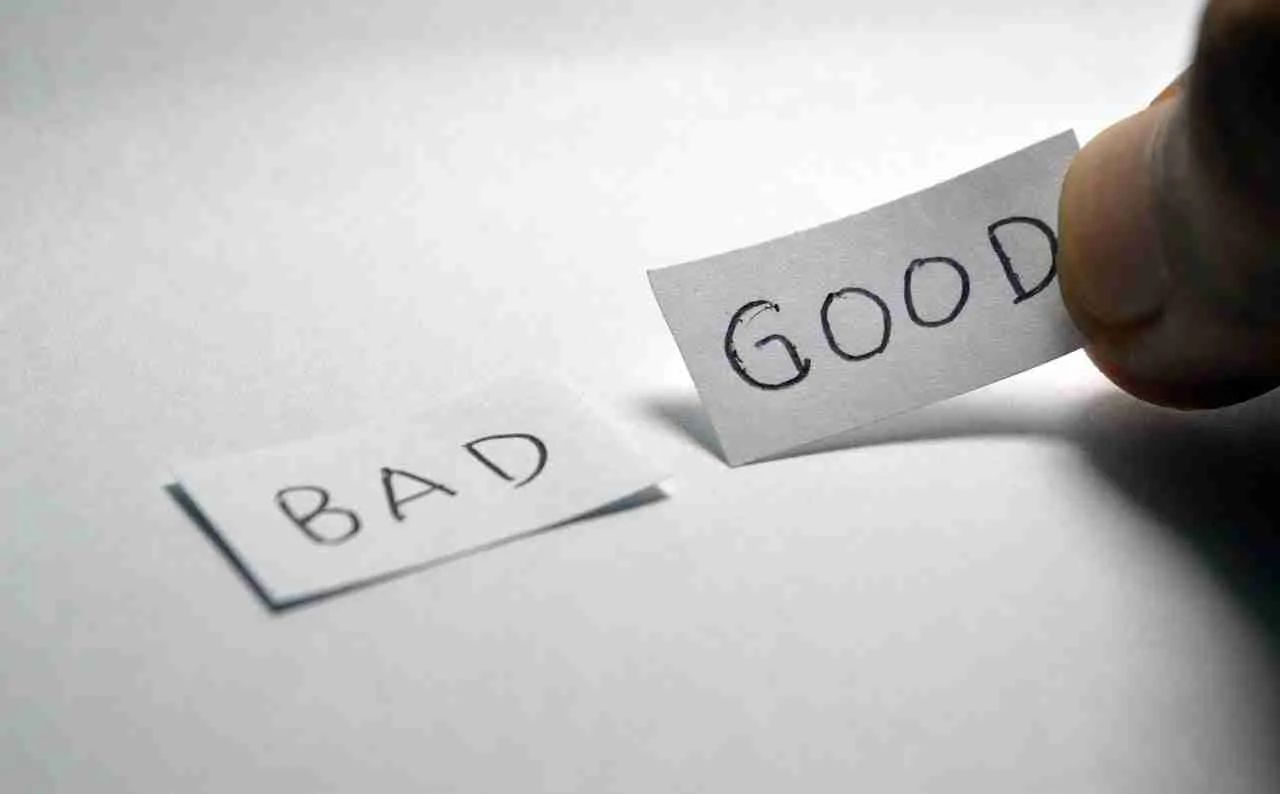 Choosing positivity: a hand selecting a paper labeled "good" over one labeled "bad.