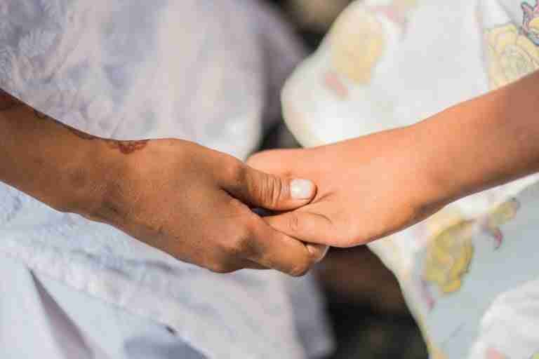 A close-up of two people holding hands in a gesture of comfort, support, or friendship. joint loans
