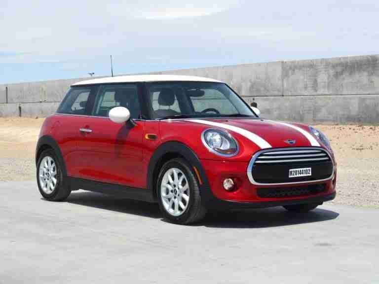 A red mini cooper parked on an open area with a concrete floor and a clear sky above. little loans bad credit