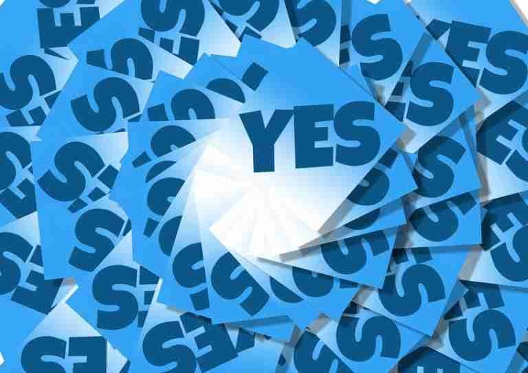 A pile of blue papers featuring a bold "yes!" overlapping one another in a haphazard manner.