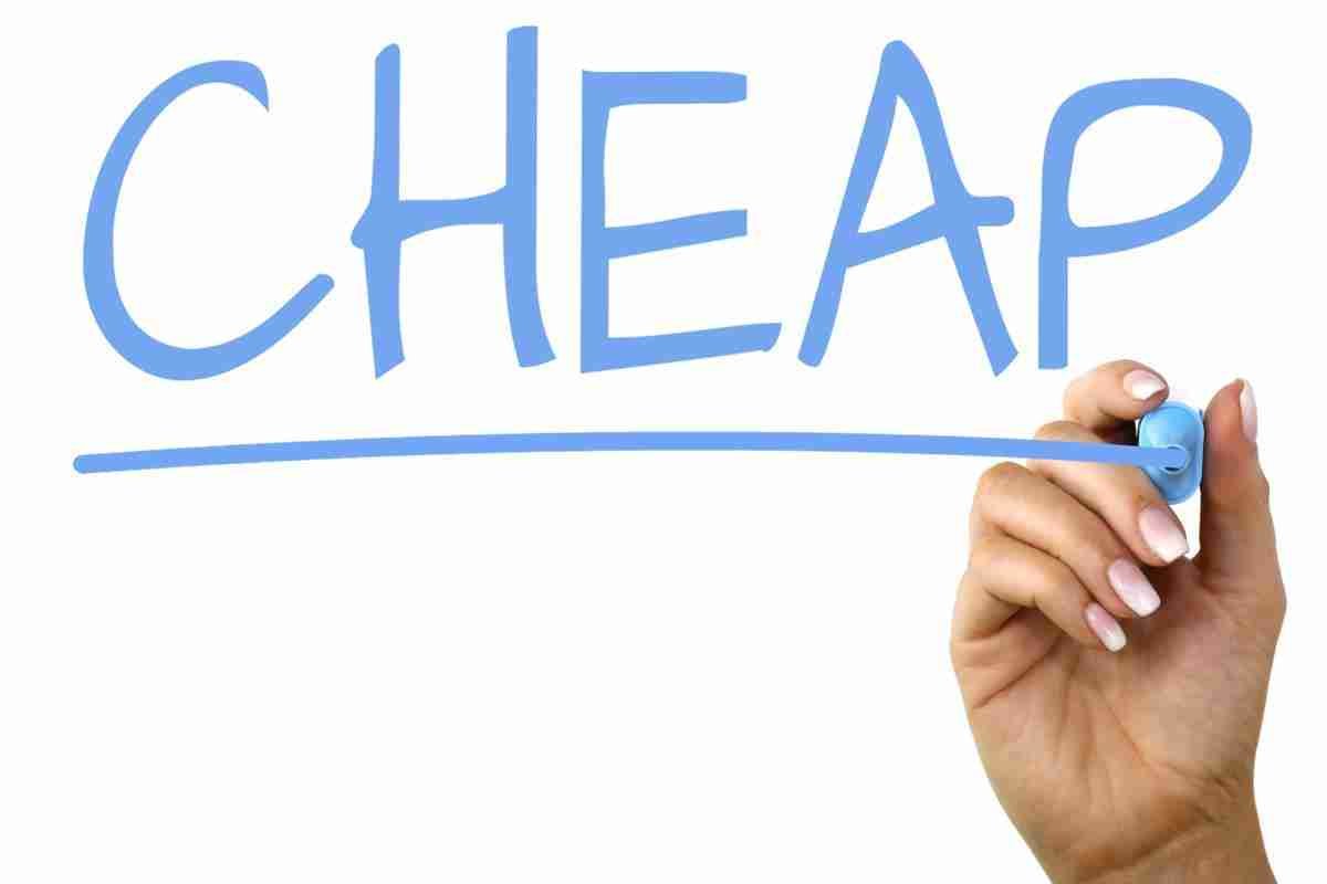 A hand with a blue marker finishing the letter 'P' in the word "CHEAP," which is written in a large blue font on a white background.