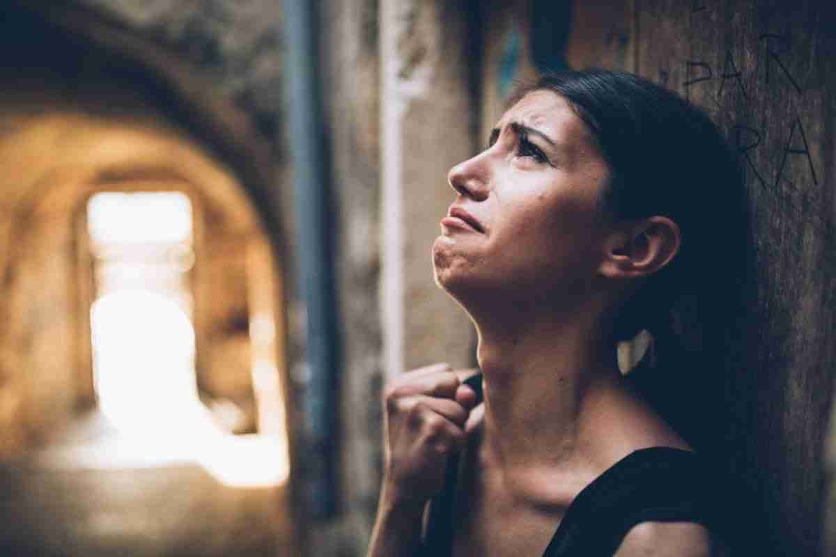 A woman appears contemplative as she looks upwards with a blurred archway in the background. desperate for a loan.