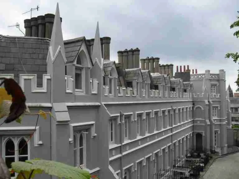 A row of traditional Victorian houses with distinct architectural detailing, including sharp gables and multiple chimneys, under a cloudy sky. Some foliage is visible in the foreground. secured homeowner loans