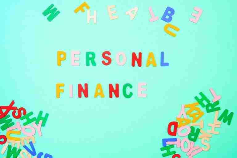 Colorful magnetic letters on a light teal background spelling out "PERSONAL FINANCE" in the center, surrounded by a scattered assortment of other letters.