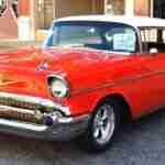 A classic red 1957 Chevrolet Bel Air parked on the street with a for-sale sign in the side window. car finance company