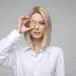 Borrow 50 Pounds Today: Discover the Fastest Ways to Get Cash A woman in a white shirt holding a gold coin over her right eye. borrow 50 pounds.