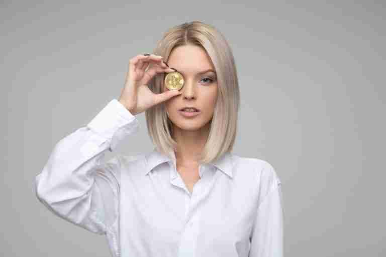 A woman in a white shirt holding a gold coin over her right eye. borrow 50 pounds.