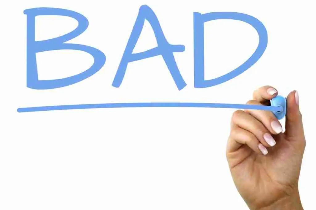 A hand holding a marker pen appears to be writing the word "BAD" in blue, with an underline, on a white background. Bad credit loans online.