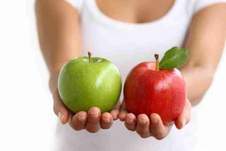 A person holding a green apple in their left hand and a red apple with a leaf in their right hand against a white background. go compare loans bad credit.