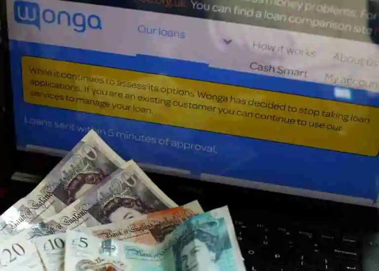 British currency notes on a laptop keyboard with the screen displaying the Wonga website and a message indicating that Wonga has stopped taking loan applications. 50 Pound Loans