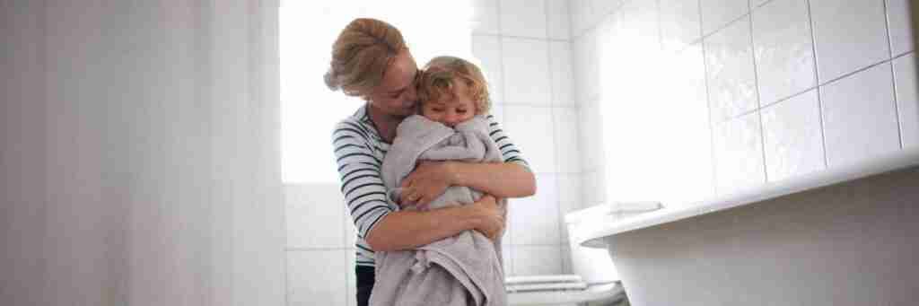 A woman hugging a towel-wrapped child in a bright bathroom. Switching Mortgages