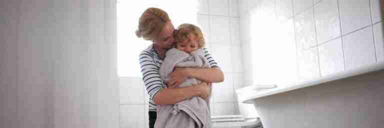 A woman hugging a towel-wrapped child in a bright bathroom. Switching Mortgages