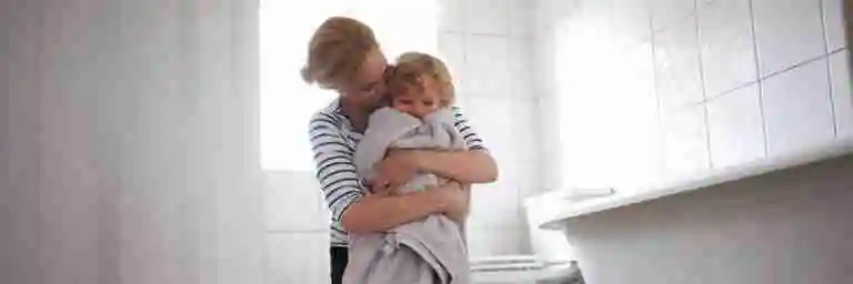 A woman hugging a towel-wrapped child in a bright bathroom. Switching Mortgages