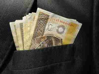 A stack of British pound banknotes, suggestive of cheap short-term loans, peeking out from a dark suit jacket's breast pocket.