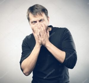 man with hands covering mouth in desperation