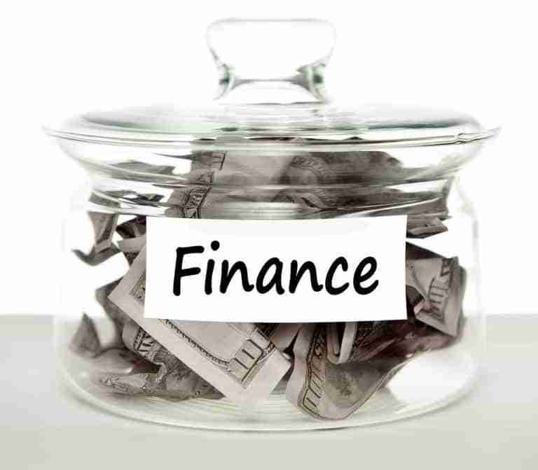 A glass jar filled with crumpled currency bills and labeled with a tag reading "loans anyone can get.
