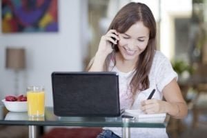 no fee loans no guarantor girl on mobile phone and laptop smiling