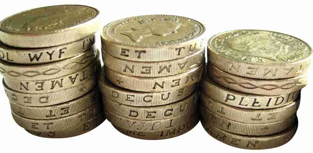 Three stacks of British pound coins representing personal loans poor credit on a plain background.