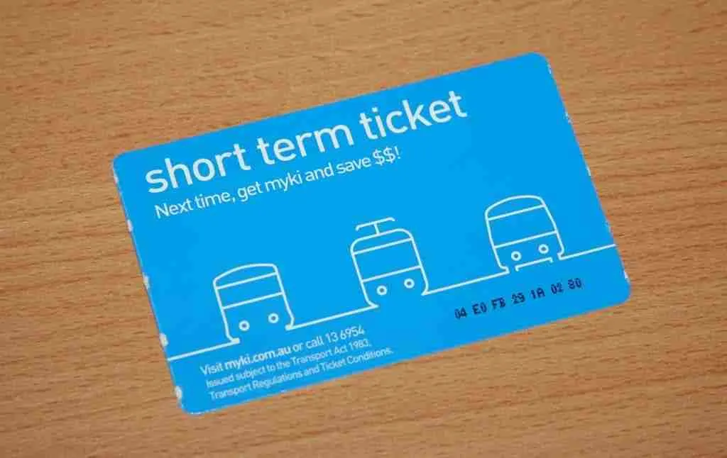 A blue short-term loans easy repayment public transportation ticket lying on a wooden surface, prompting the user to switch to a permanent myki card for savings.